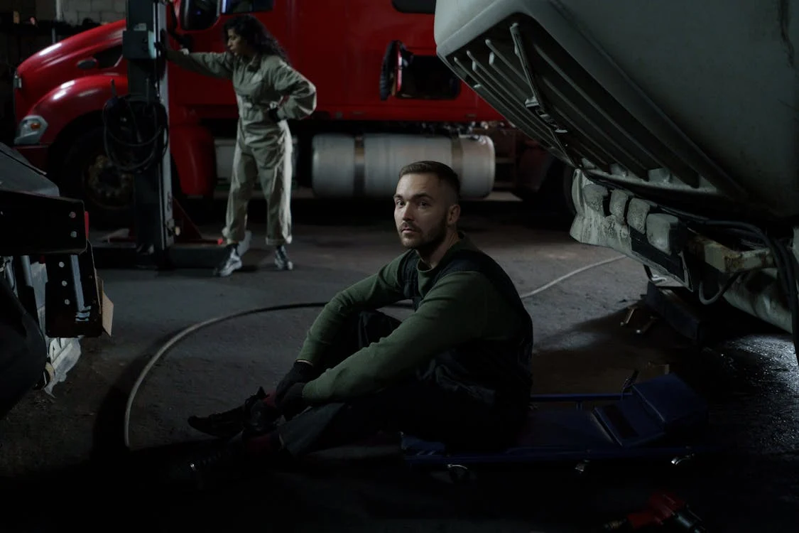 diesel mechanic seated on dolly in garage